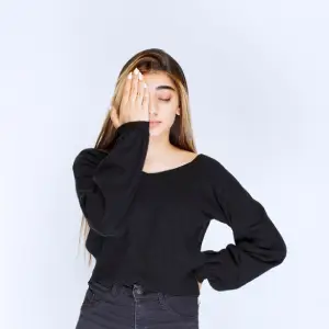 Chica joven víctima de maltrato se tapa la mitad derecha de su rostro con su mano derecha como símbolo de protesta en contra del maltrato a la mujer.