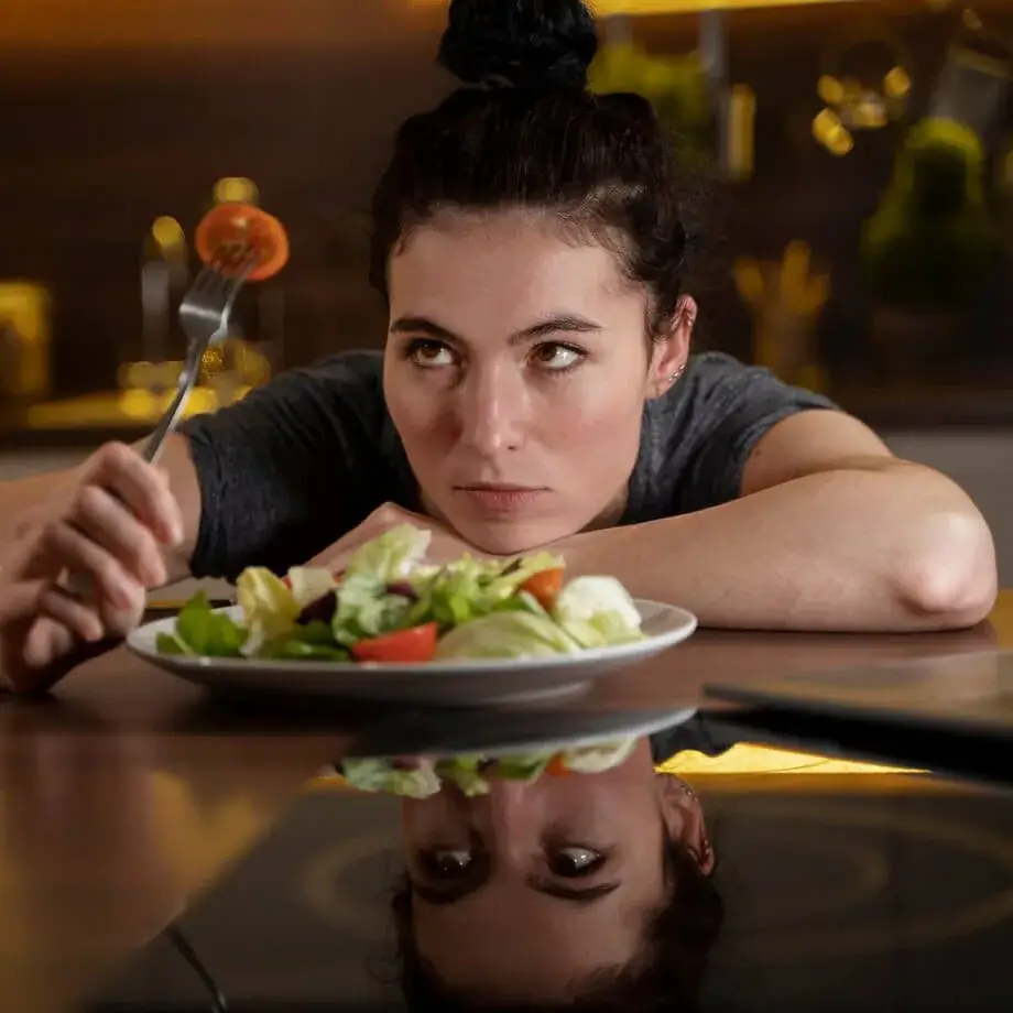 Joven con TCA contemplando un tomate en el tenedor manifestando desagrado por la comida.